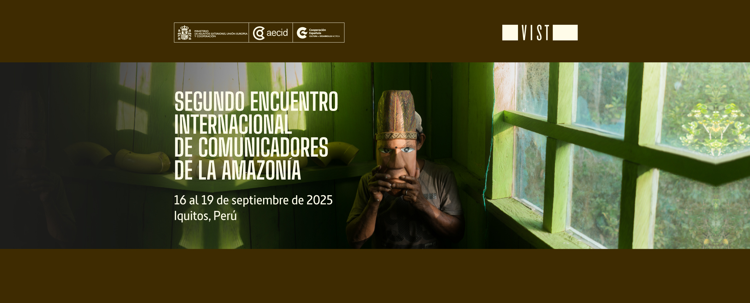 Foto de un hombre sentado en la esquina de una habitación verde de madera y sobre su rostro sostiene una máscara de un personaje indígena. La ventana de la habitación da hacia un bosque tupido. Al costado izquierdo de la foto se lee SEGUNDO ENCUENTRO INTERNACIONAL DE COMUNICADORES DE LA AMAZONÍA, 16 al 19 de septiembre, Iquitos, Perú. En la franza superior aparecen los logotipos de AECID-PROGRAMA ACERCA y la Fundación Vist Project.